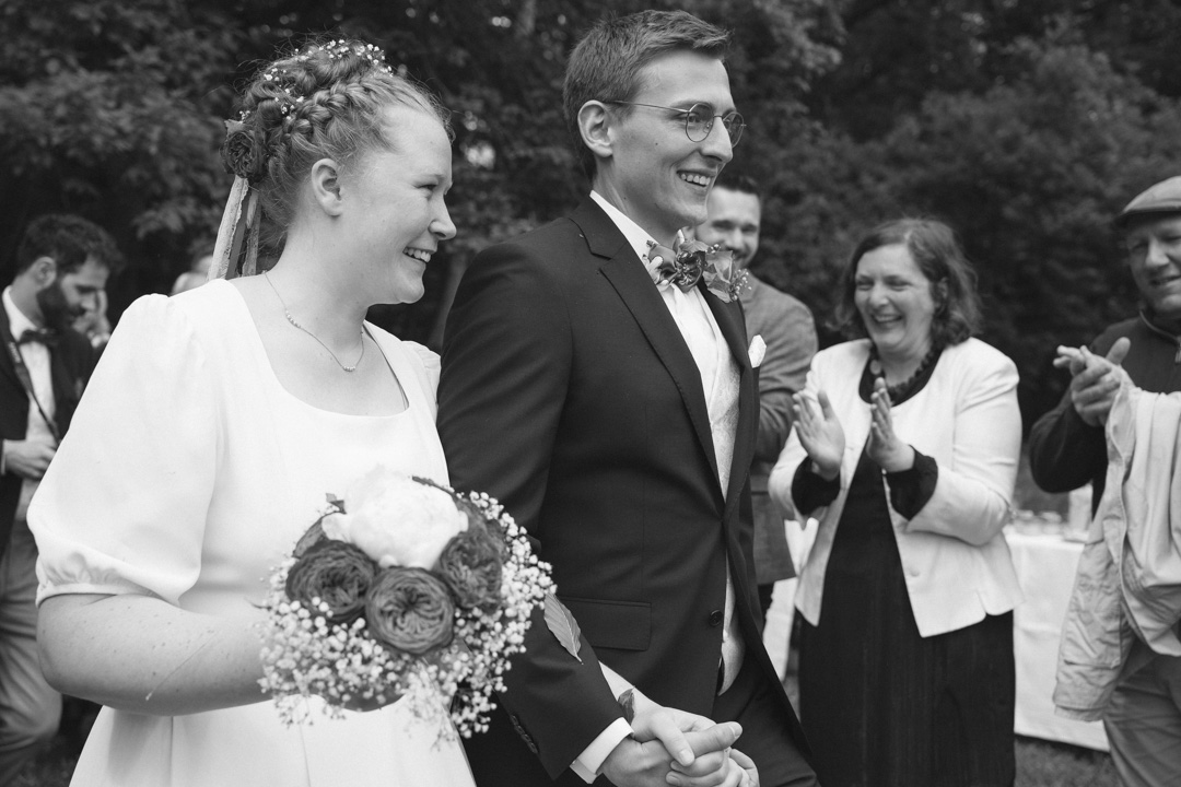 glückliches Brautpaar in schwarz-weiß mit klatschenden Gästen nach Trauung in Tübingen