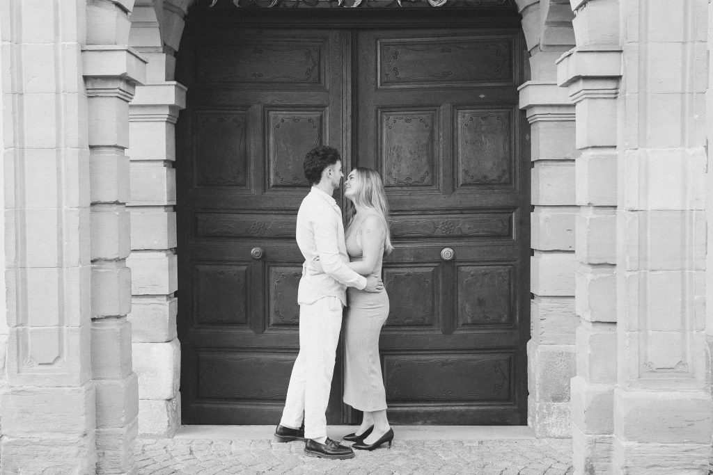 elegantes Paar umarmend in schwarz weiß steht in Tübingen vor alter Türe