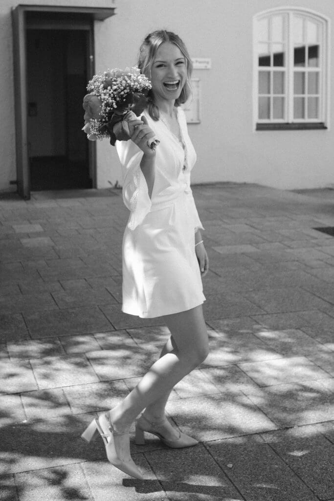 Foto in schwarz-weiß einer glücklichen Braut vor dem Standesamt nach Hochzeit